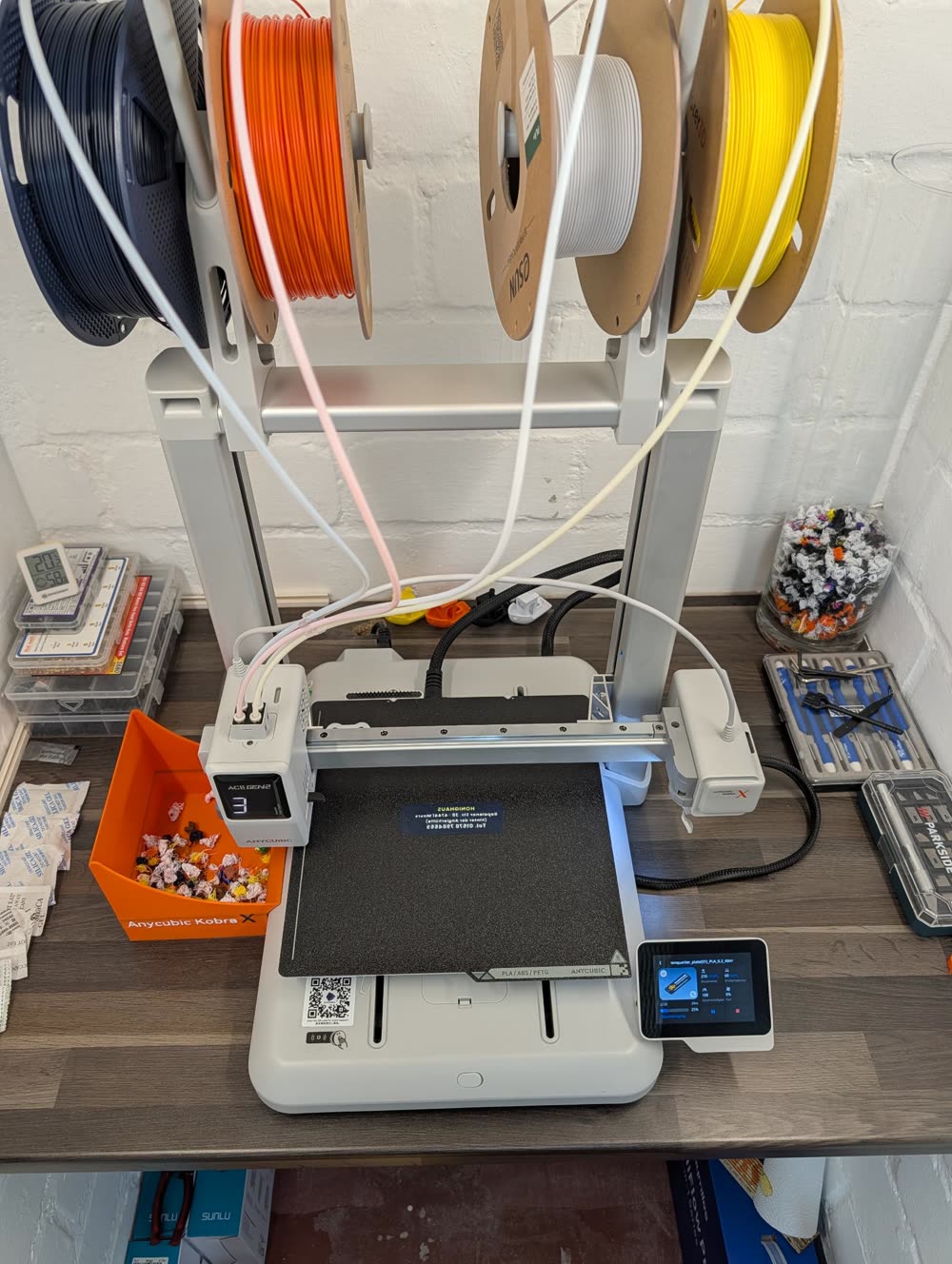 3D-Drucker Anycubic Kobra X mit vier Filamentrollen in Dunkelblau, Orange, Weiß und Gelb