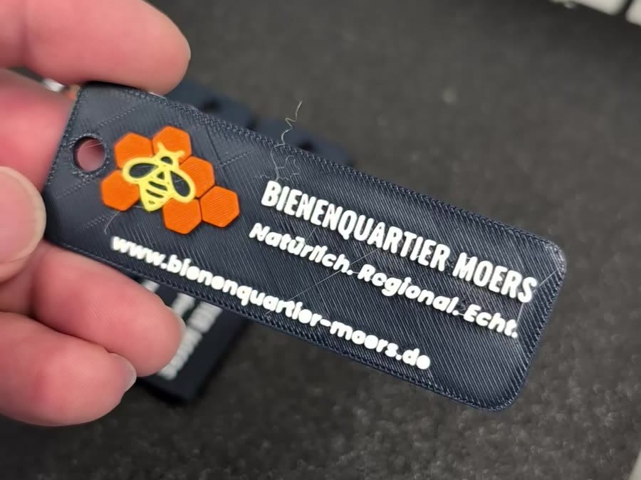 Vorderseite des Schlüsselanhängers mit Bienen-Logo, Slogan und Webadresse